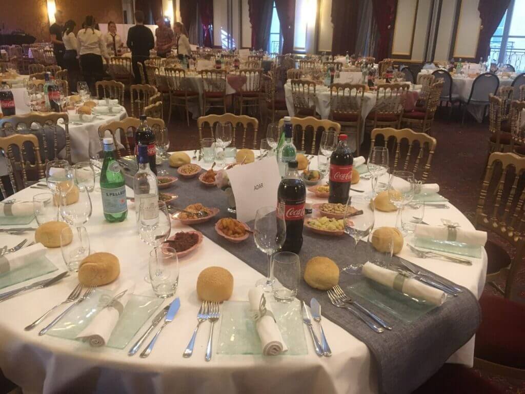 Grande salle de réception préparée par Metsouyane Traiteur casher, avec tables rondes dressées, pains individuels, boissons et entrées variées pour mariage, bar-mitsvah ou événement sur le Bassin d’Arcachon et Bordeaux.